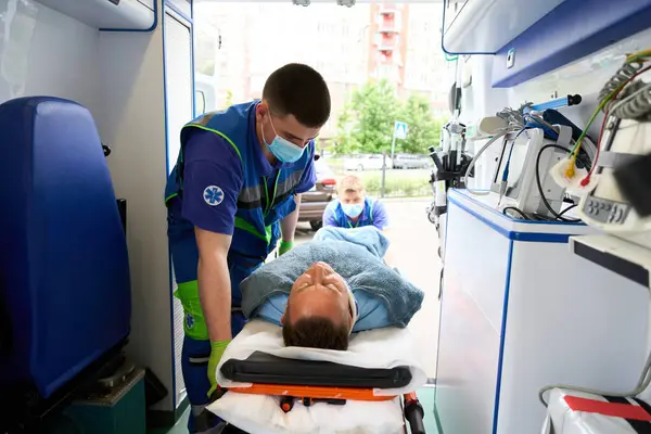 Sanitäter Uniform Entladen Einen Kranken Aus Einem Krankenwagen Moderne Ausrüstung lizenzfreie Stockfotos