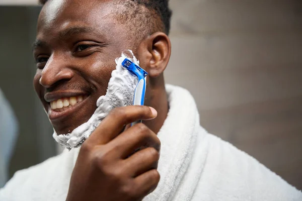 アフリカ系アメリカ人男性は使い捨てカミソリで剃り シェービングフォームを使用しています — ストック写真