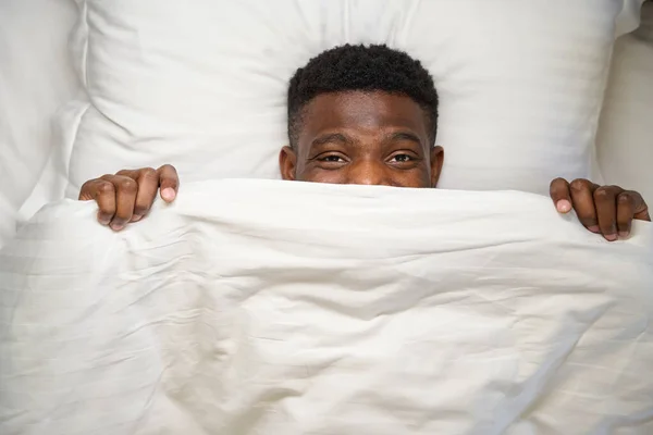 Mutlu Afrikalı Amerikalı Erkek Battaniyenin Altından Bakar Yumuşak Bir Yatağa — Stok fotoğraf