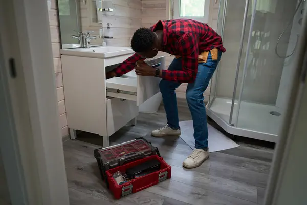 アフリカ系アメリカ人労働者は 彼のツールキットを使用して小さなバスルームの改装を行います — ストック写真