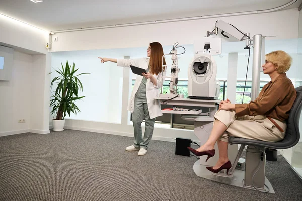 眼科医生顾问检查病人的视力 女人都在明亮的办公室里 — 图库照片