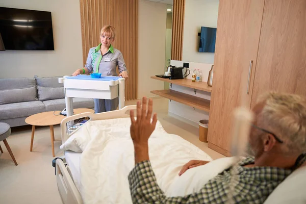 Elderly patient greets a nice nurse, a woman came into the room with an injection table