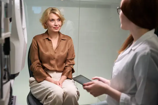 眼科医の診察を受けた中年の女性患者 明るい部屋でコミュニケーションをとる女性 — ストック写真