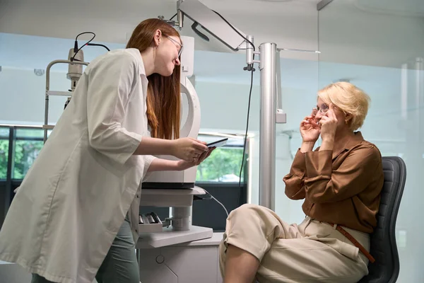 職場の眼科医は患者とコミュニケーションをとり 医師はプロのガジェットを使用しています — ストック写真