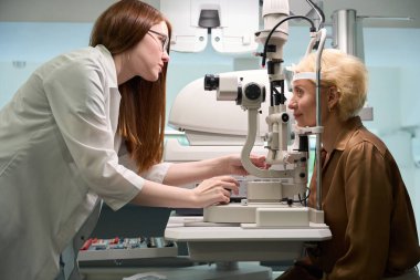 İş yerindeki oftalmolog modern bir diyotrimetre kullanıyor. Müşteri cihazın karşısında.