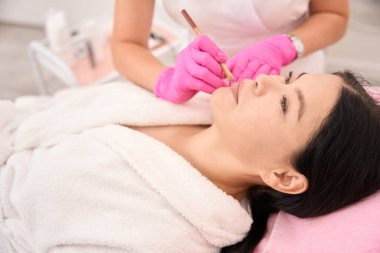 İşlemden önce müşterilerin dudaklarını işaretlemek için, usta özel bir kalem kullanır