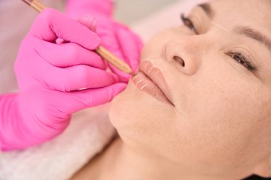 İşlemden önce müşterinin dudaklarını işaretleyen usta, bir kalem kullanır.