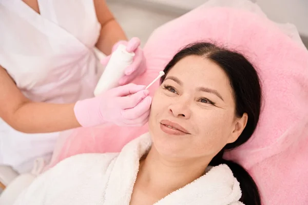 Beauty master applies cream to the clients eyebrows, modern equipment in the room