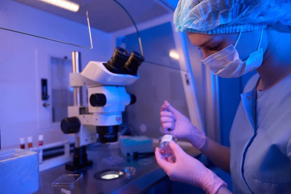 Cientista Fêmea Sentada Mesa Frente Microscópio Preparando Líquido Garrafa Reagente — Fotografia de Stock