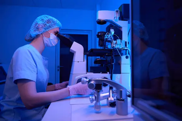 顕微鏡およびマイクロマニピュレーターを用いた細胞可塑性精子注入手順を実施する女性胚学者 — ストック写真