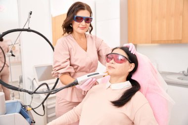 Bir kozmetoloji kliniğinin Asyalı müşterisi lazer yüz kıllarını aldırma prosedürüne tabi tutuluyor. Salonun hoş bir iç mekanı var.