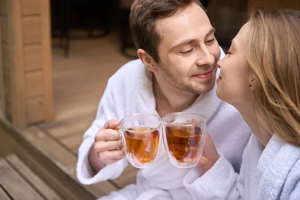 ローブのロマンチックなカップルは ドアステップに座って朝のお茶を飲んでいる間 愛のサインとして鼻をこすります — ストック写真