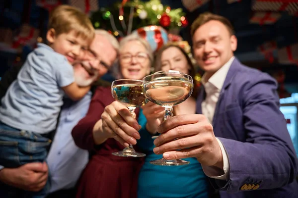 Group of people holding glasses with champagne celebrating New Year in restaurant expressing happiness