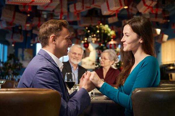 カフェでクリスマスディナーで手を握る笑顔の女性と男性 — ストック写真