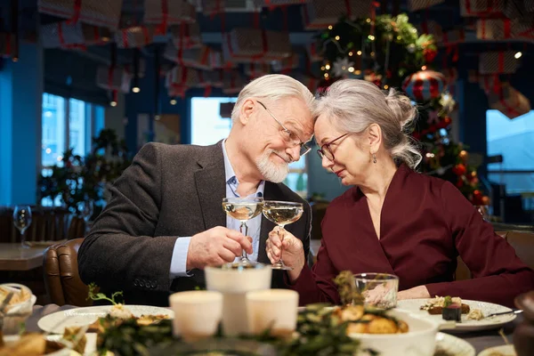 Happy aged man and woman with glasses of champagne celebrating New Year Eve together in restaurant