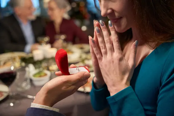 レストランで赤い箱のクリスマスの提案のリングを持つかなり驚いた女性および認識できない男 — ストック写真
