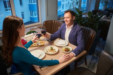 Kadın ve erkek el ele tutuşur ve restoranda yeni yıl yemeği boyunca kadehleri tokuştururlar.