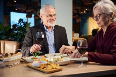 Mutlu yaşlı çift restoranda yeni yıl arifesini şenlikli bir yemekle kutluyor.