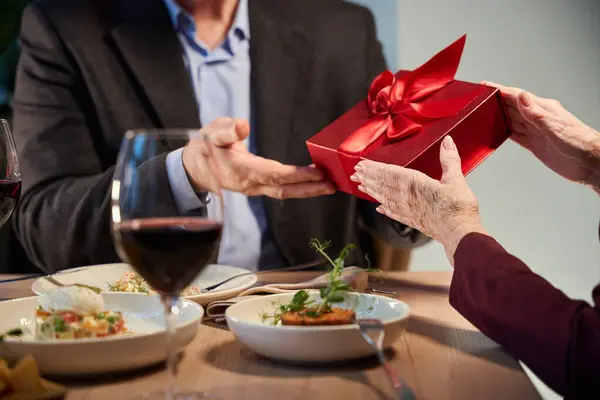 Woman hands giving present box to man while celebrating winter holiday in cafe