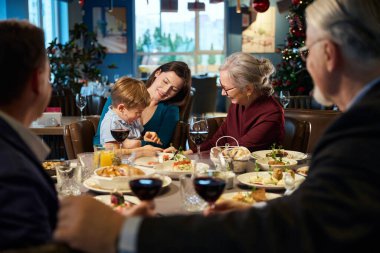 Yeni yıl kutlamaları sırasında restoranda küçük çocukla iletişim kurmaktan memnun olan yaşlı bir kadın.