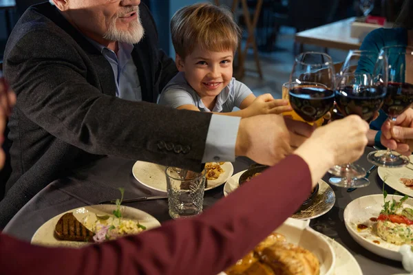 Family holding glasses with wine, toasting while celebrating Christmas in the restaurant