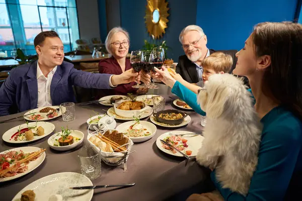 Joyful people with wine glasses toasting celebrating Christmas together enjoying festive atmosphere in restaurant