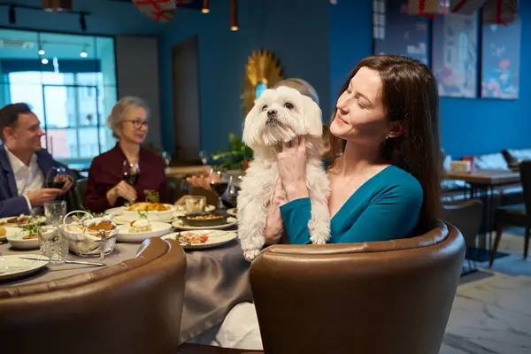 微笑的女人牵着她的狗在节日餐厅和家人一起欢度圣诞 — 图库照片