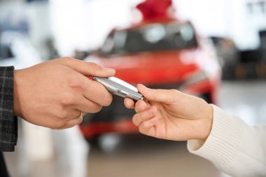 Bilinmeyen satıcı, başarılı bir satın alma sonrasında kadın müşteriye yeni otomobilin anahtarlarını veriyor.