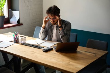 Genç, yorgun, Kafkas işadamı çalışma masasında çalışırken baş ağrısı çekiyor. İşçilik ve tükenme kavramı