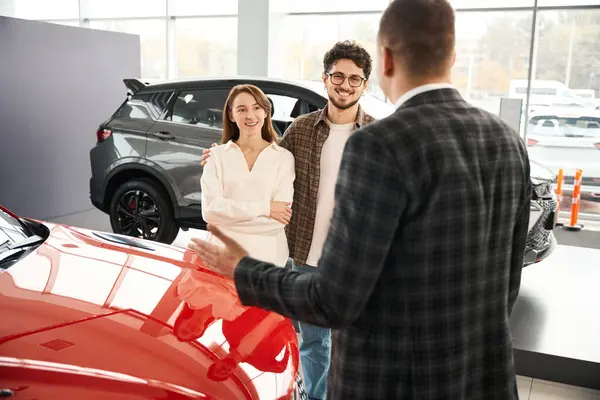 Back View Salesman Dealership Talking Young Couple Presenting Automobiles Man — Stock Photo, Image