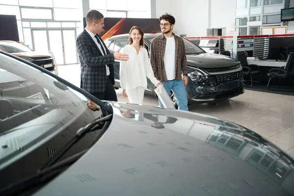 Cheerful Couple Visiting Automobile Showroom Exhibition Having Conversation Salesman New — Stock Photo, Image