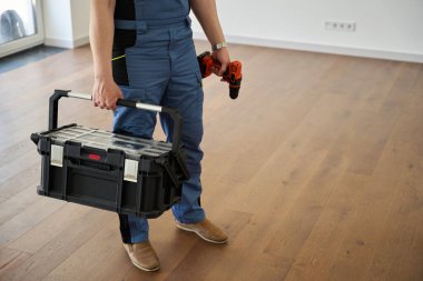 Partial image of repairman with blueprint and drill in new modern comfortable townhouse before repair