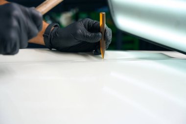 Process of using a special gadget to level out body dents, a man works wearing protective gloves