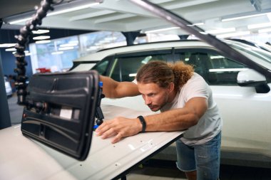 Straightening man uses a straightening pump to repair a white car