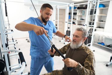 Doctor is working with a patient in the gym, a specialist is using a special simulator