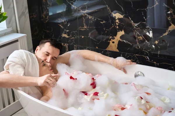 Newlyweds Soak Foam Bath Rose Petals Man Gently Hugs Kisses — Fotografia de Stock