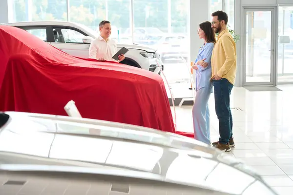 Car Dealership Consultant Presents Car Red Cover Buyer His Wife — Stock Photo, Image