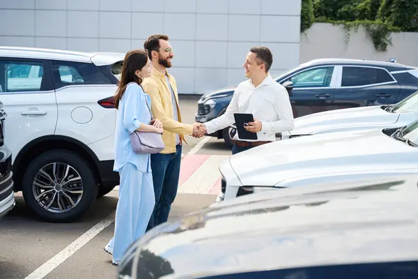 Car Dealership Employee Communicates Couple Clients Test Drive Men Shake — Stock Photo, Image