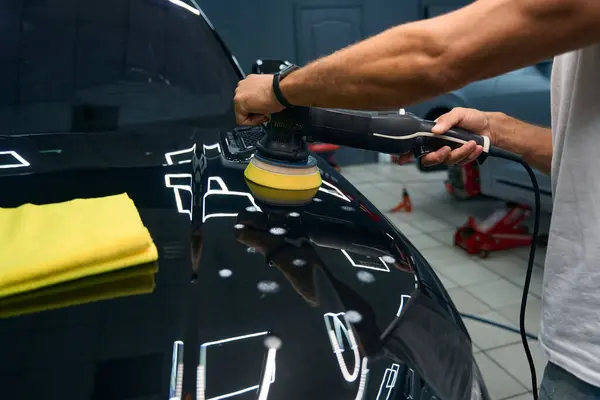 Man Car Repair Shop Polishes Hood Black Car Uses Grinder — Fotografia de Stock