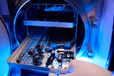 Klinikte ameliyattan önce doktor elinin histeroskop parçalarıyla açtığı tıbbi alet dolabını kapatın.