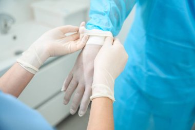 Ameliyattan önce erkek doktorun lateks eldiven giymesine yardım eden kadın hemşire görüntüsü. Sağlık ve hijyen