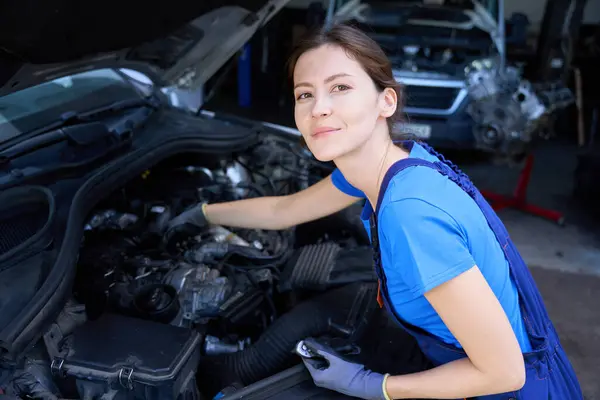 Kobieta Mechanik Pracuje Kombinezonach Pod Maską Samochodu Naprawia Silnik — Zdjęcie stockowe