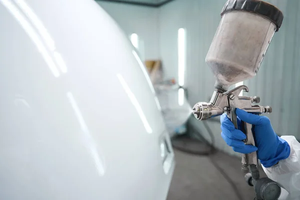 Process of painting a car with a special painting apparatus, a man works in protective equipment