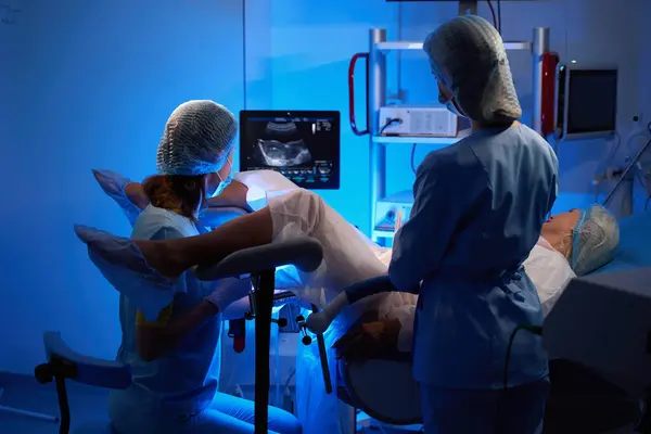 女性医師および看護師は 生殖クリニックで女性患者の胚移植を行っている間 モニターを観察します エンベロジーとバイオテクノロジー — ストック写真