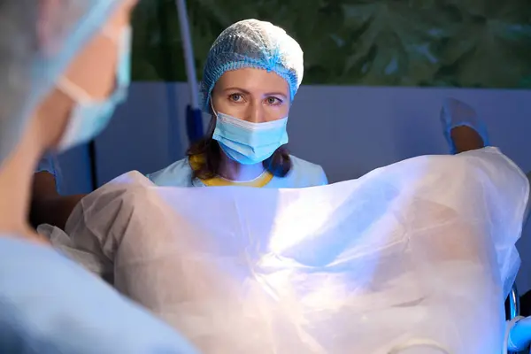 女性の医師と看護師は 生殖クリニックで作られた女性の患者のための人工受精を行っている間 お互いを見つめ合っています エンベロジーとバイオテクノロジー — ストック写真