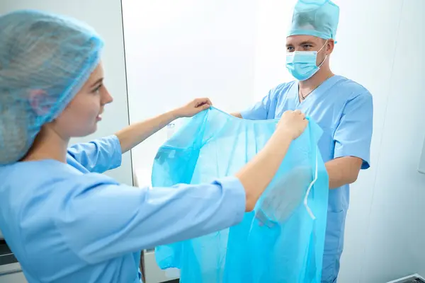 Female Nurse Helping Male Doctor Put Medical Gown Surgery Clinic — Stock Photo, Image