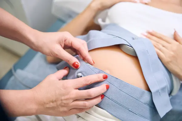 女性の婦人科医がクリニックでエッグのために妊婦の腹を準備する部分的なイメージ 妊娠検査の概念 — ストック写真