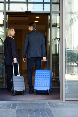 Arkadaki fotoğrafta, genç bir adam ve bir bayanın otele girerken el bagajı taşıdığı görülüyor.