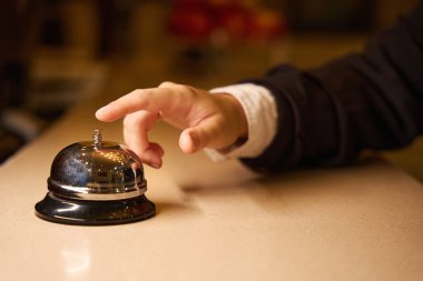 Oteldeki resepsiyonda zili çalmaya çalışan bir kadının kesilmiş fotoğrafı.