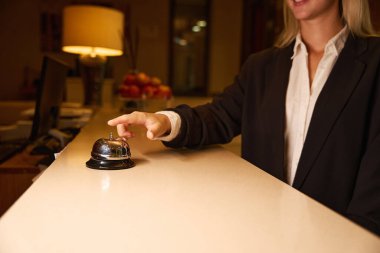 Resepsiyon alanında zili çalmaya çalışan genç bir bayanın fotoğrafı.